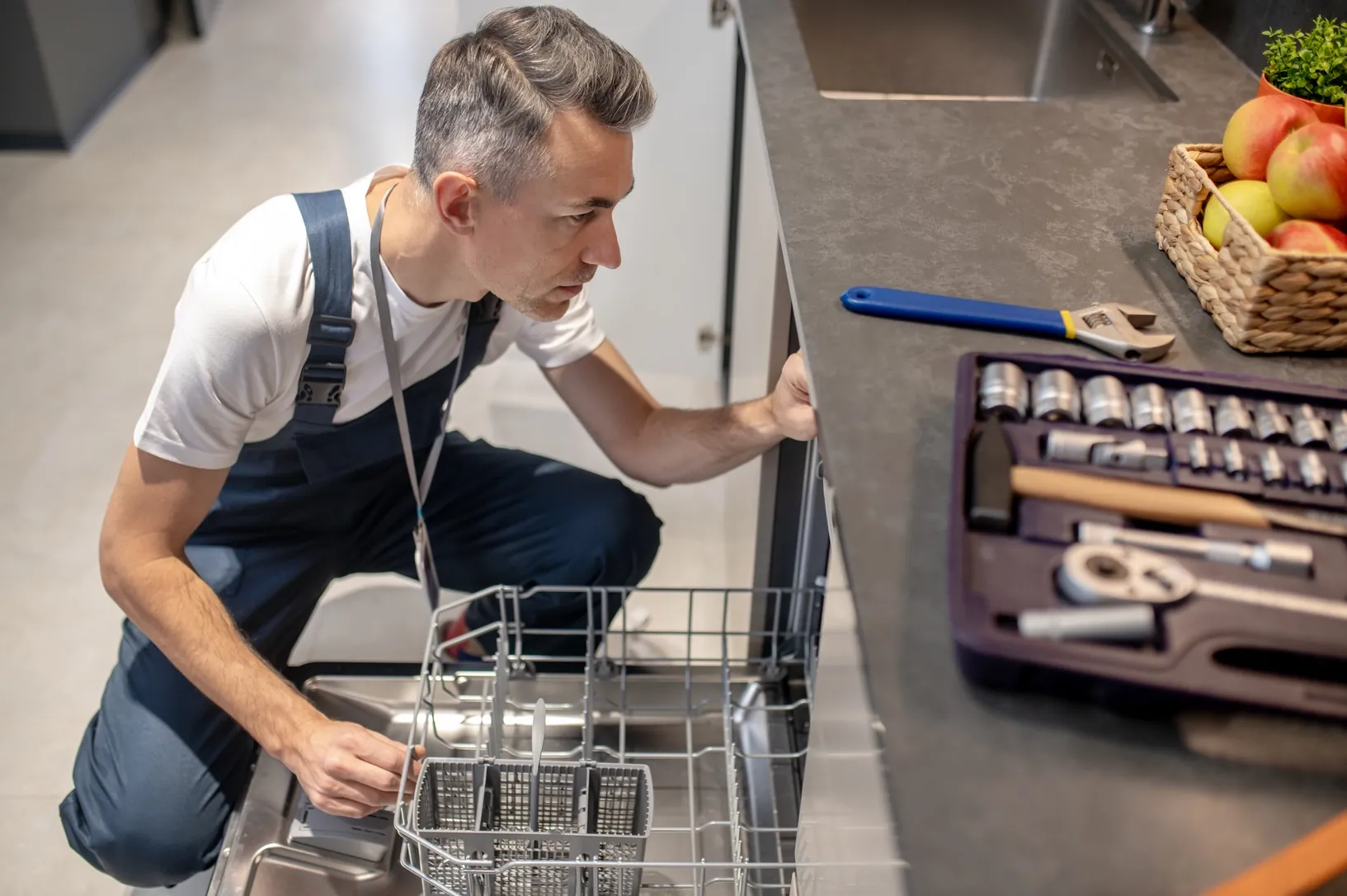 Engineer repairing an open dishwasher in a Bristol kitchen