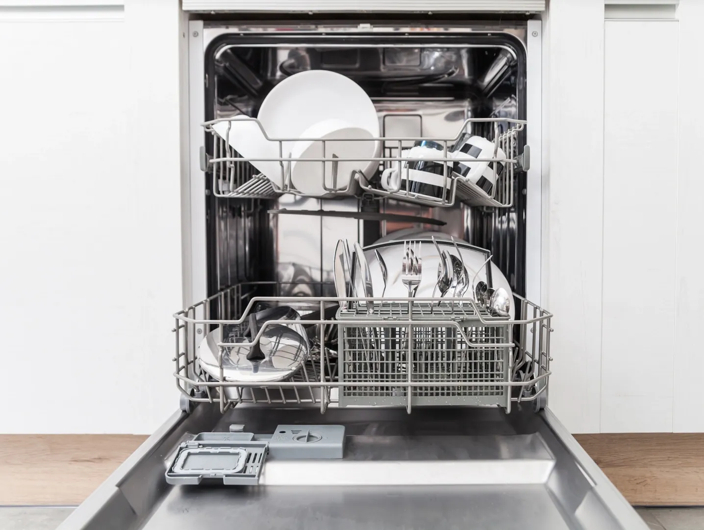 Repaired dishwasher with clean dishes in a white kitchen